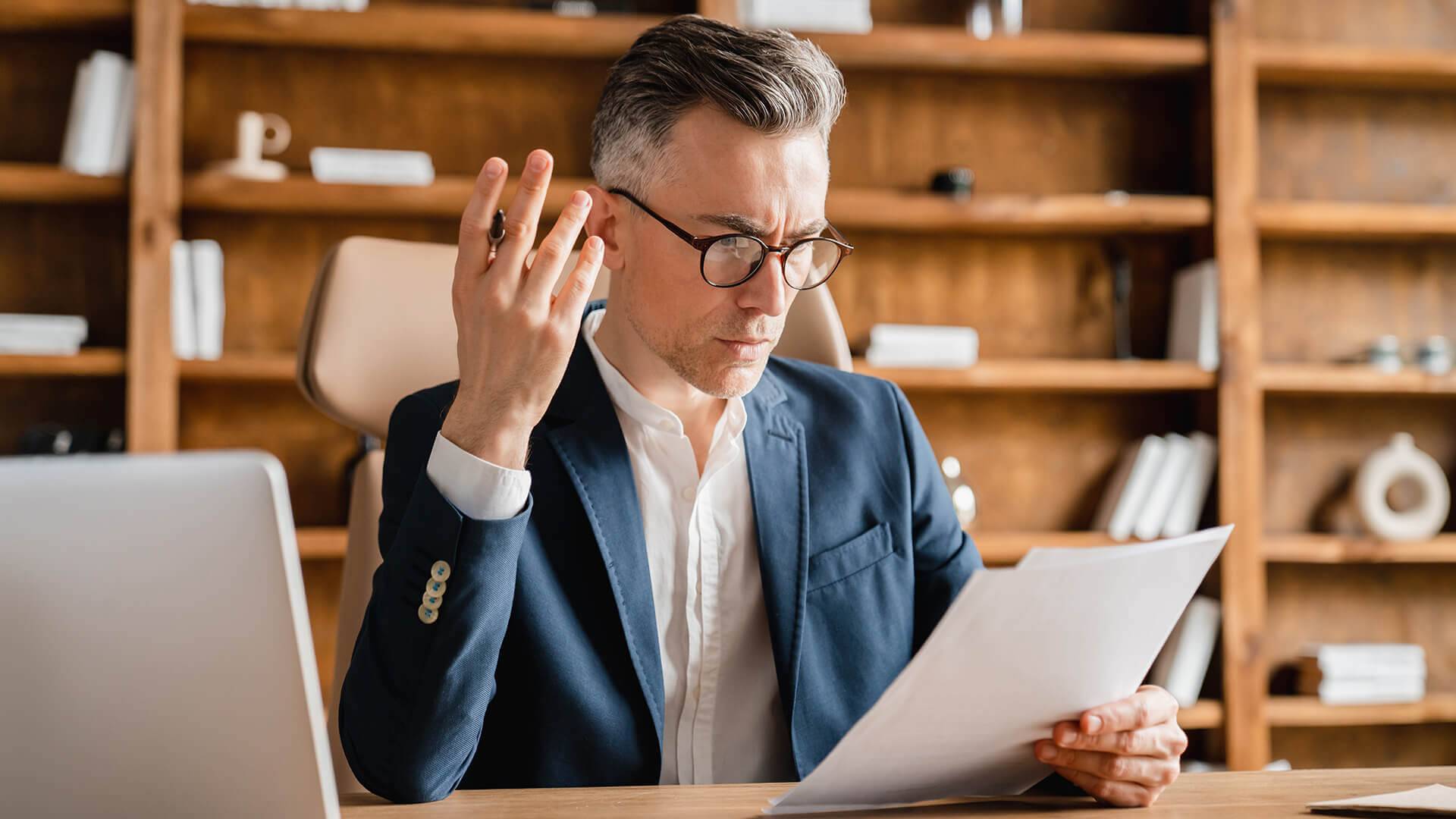 Mann h&auml;lt Papier, B&uuml;cherregal Hintergrund.
