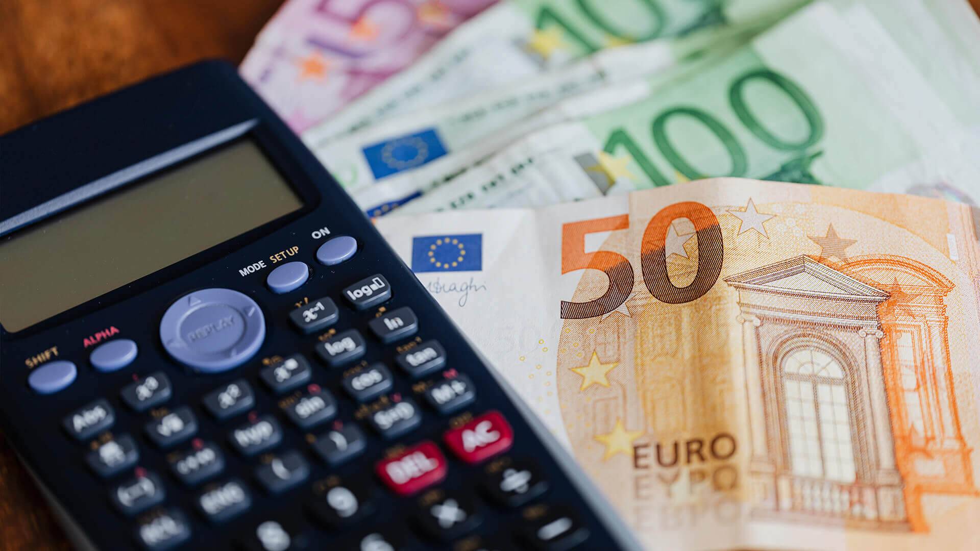 Rechner mit Papieren und M&uuml;nzen.